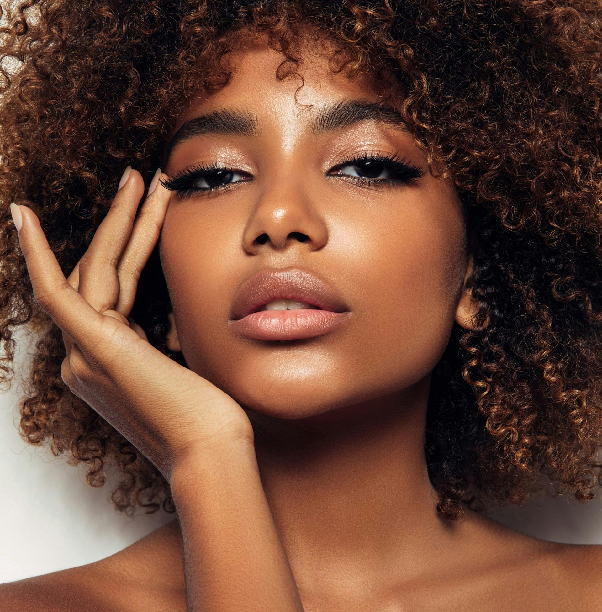 woman with afro touching the side of her eye with her hand