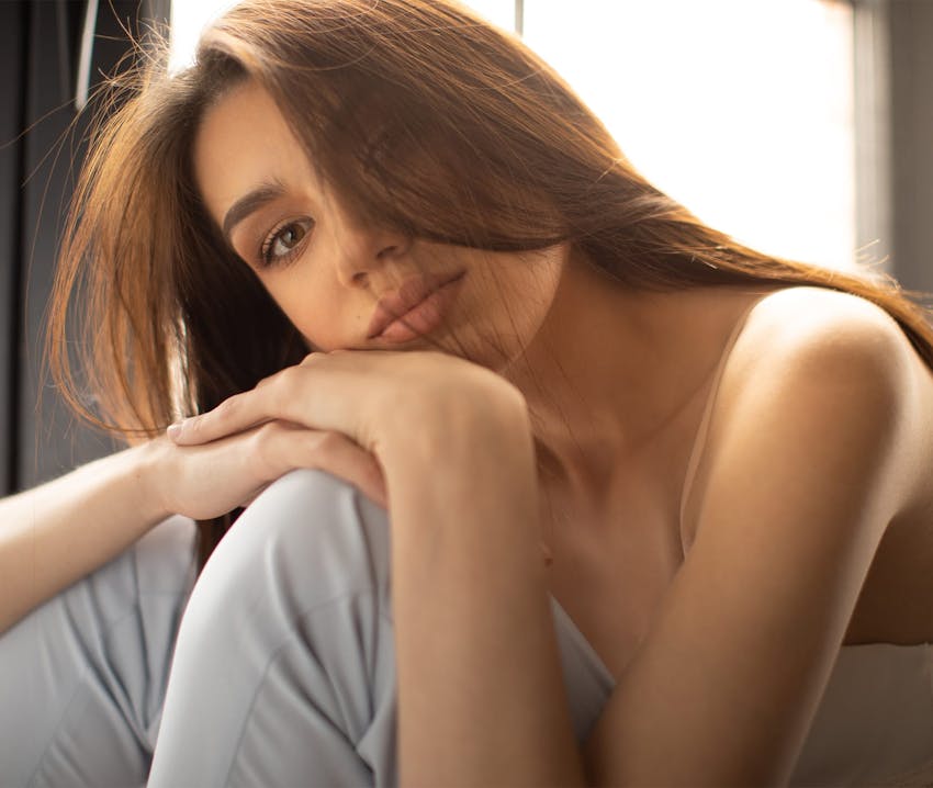 woman resting hands on head on her knee
