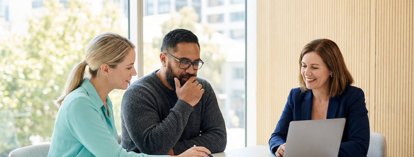 Three people sitting at an office table, reviewing notes.