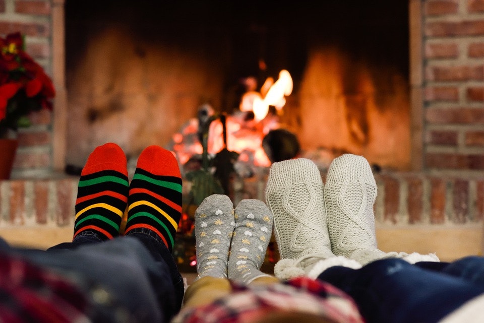 Father, daughter and mother laid down heating feet infront of fireplace