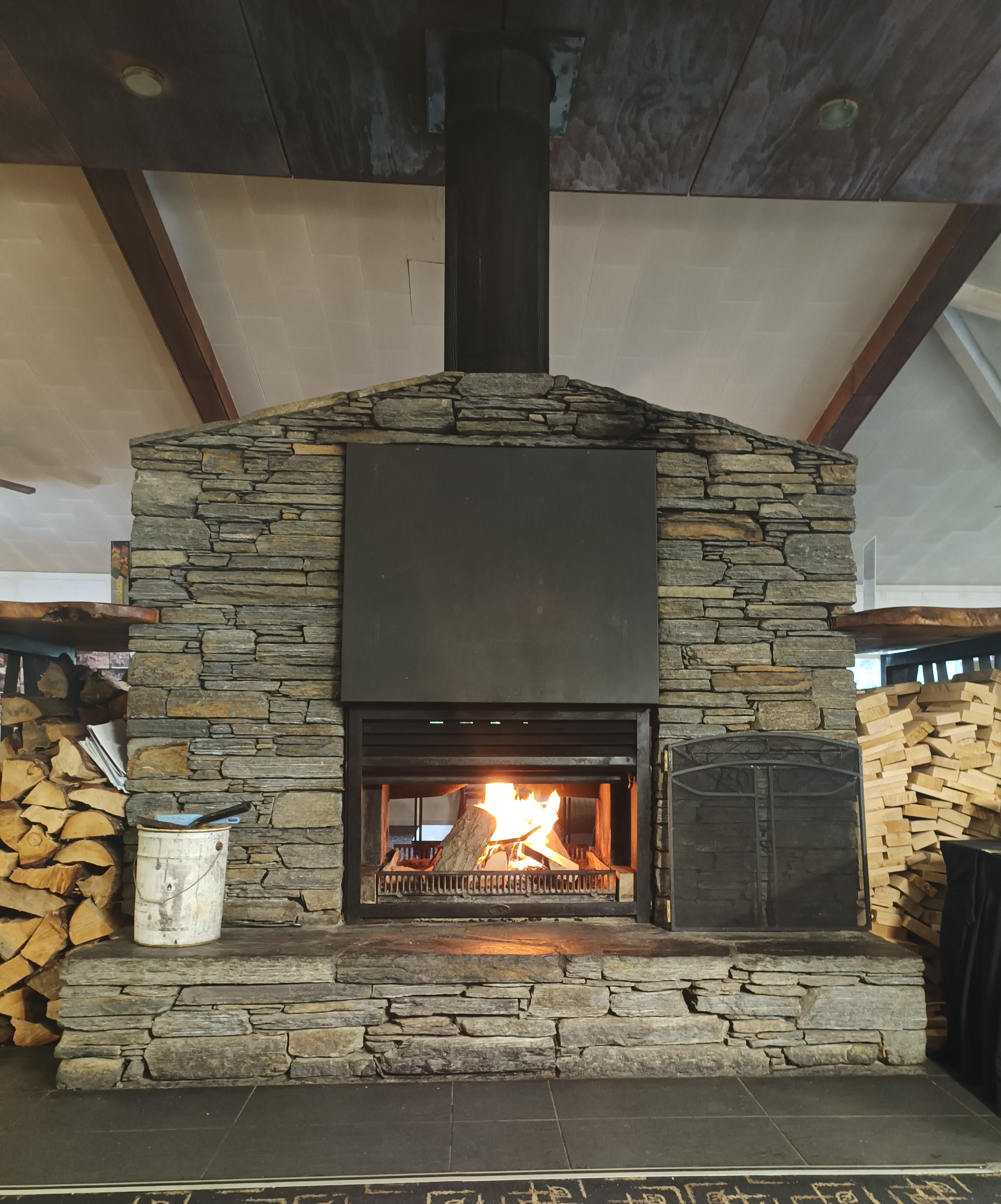 Fancy brick display fireplace in hotel with wood stacked either side