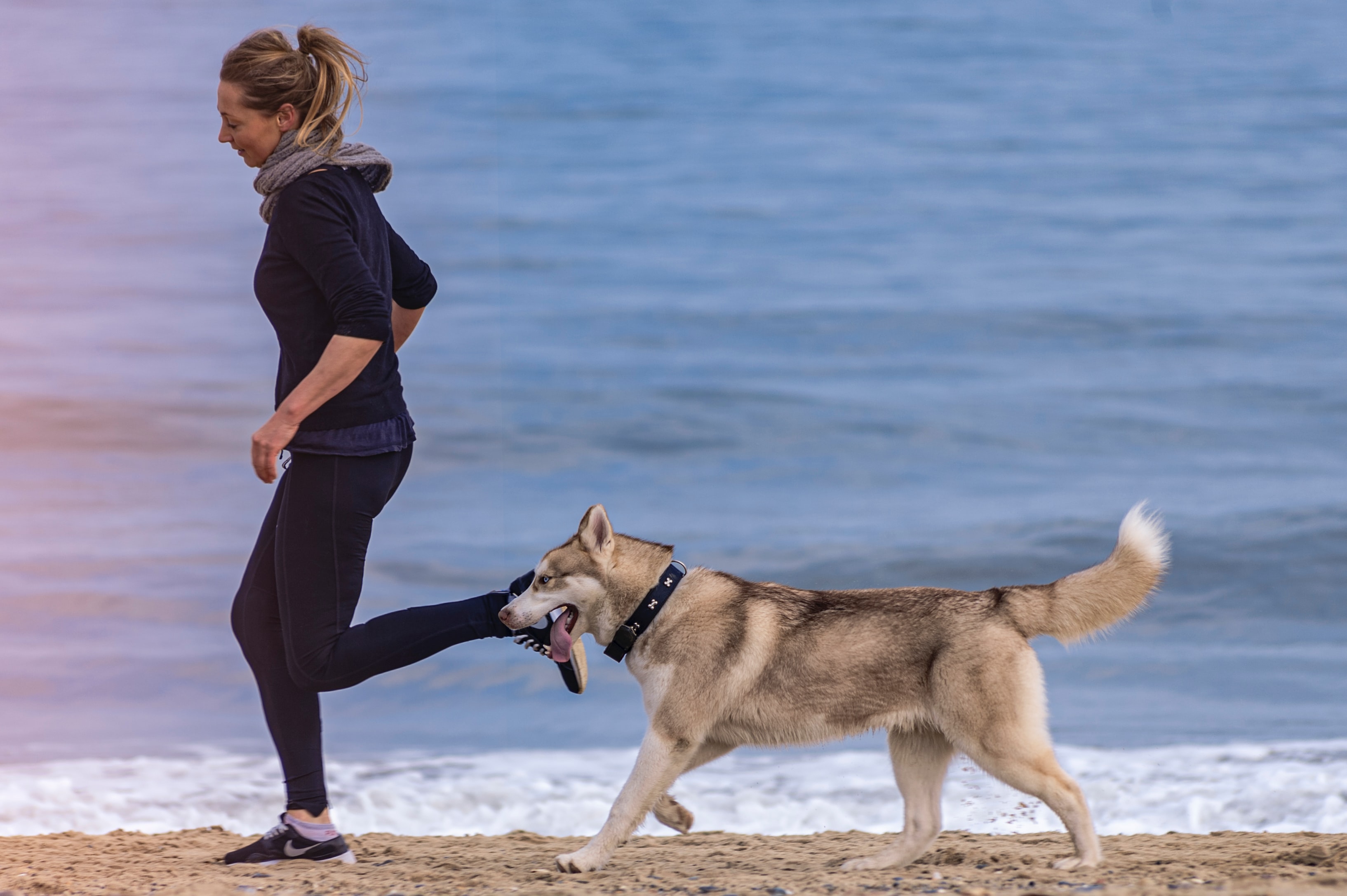 Femme qui courre sur la plage avec son chien