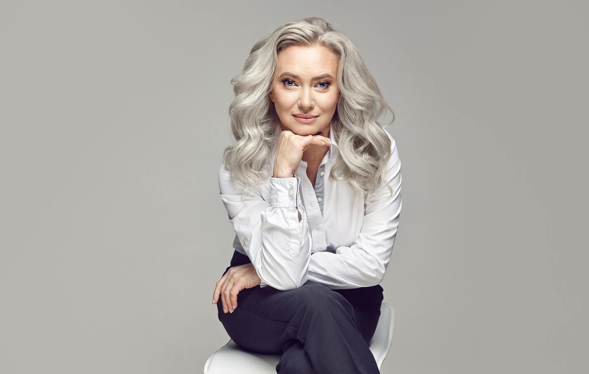woman in white blouse staring intently with hand under chin