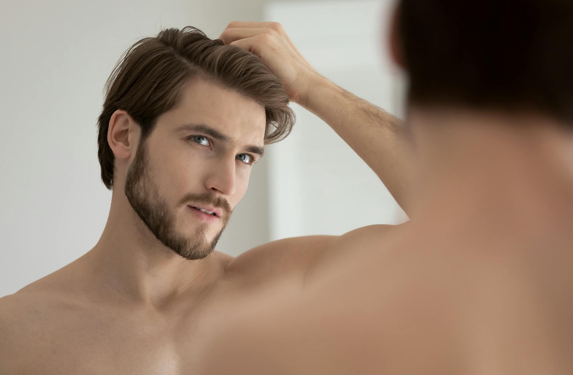 Man looking in a mirror with his hand in his hair