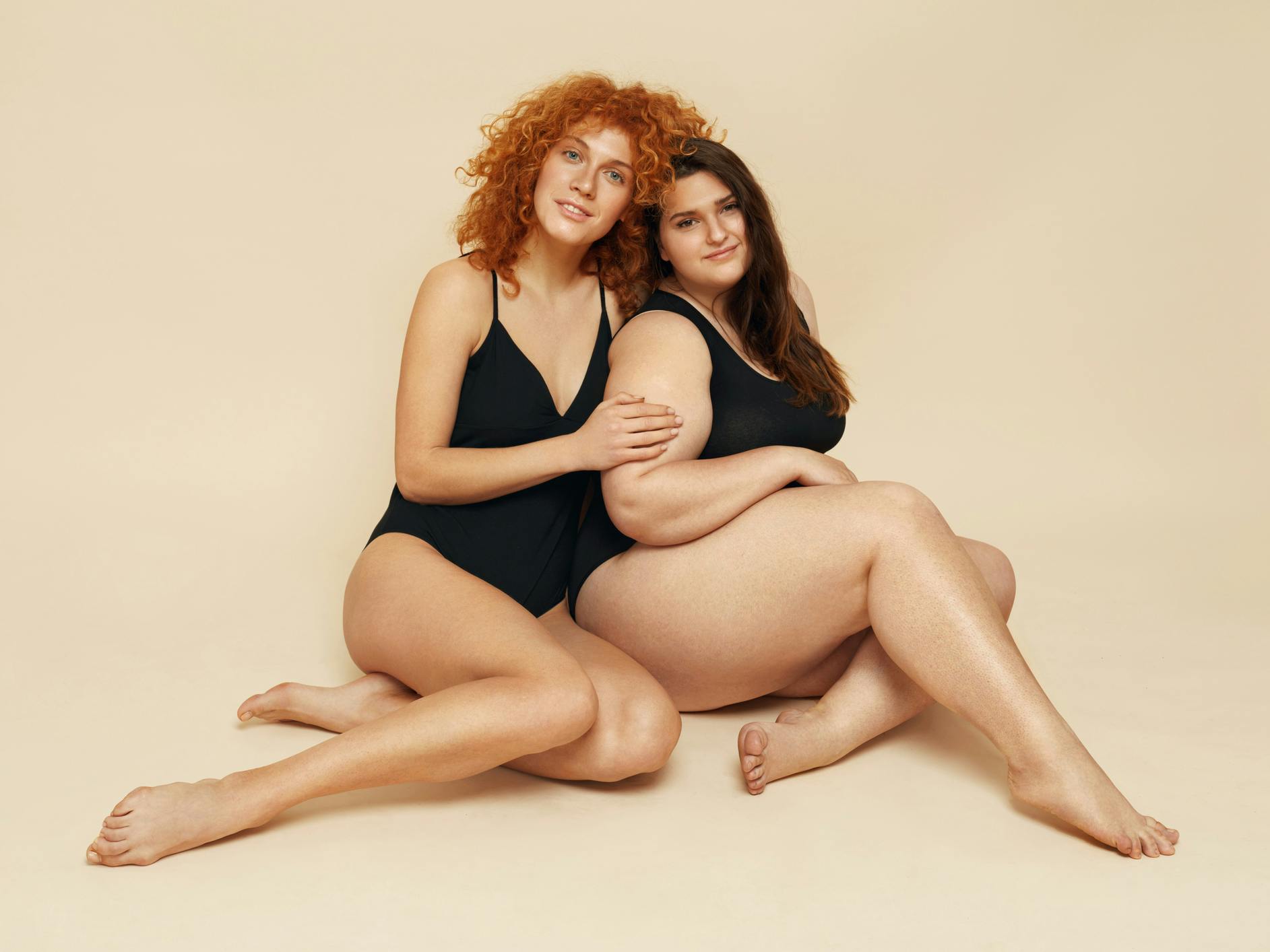 Two woman in black bikins sitting down together