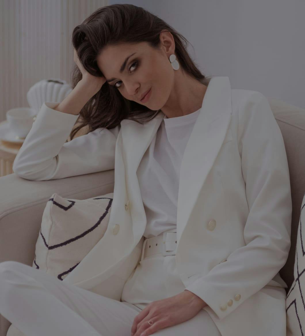 Woman in a white suite sitting on a chair