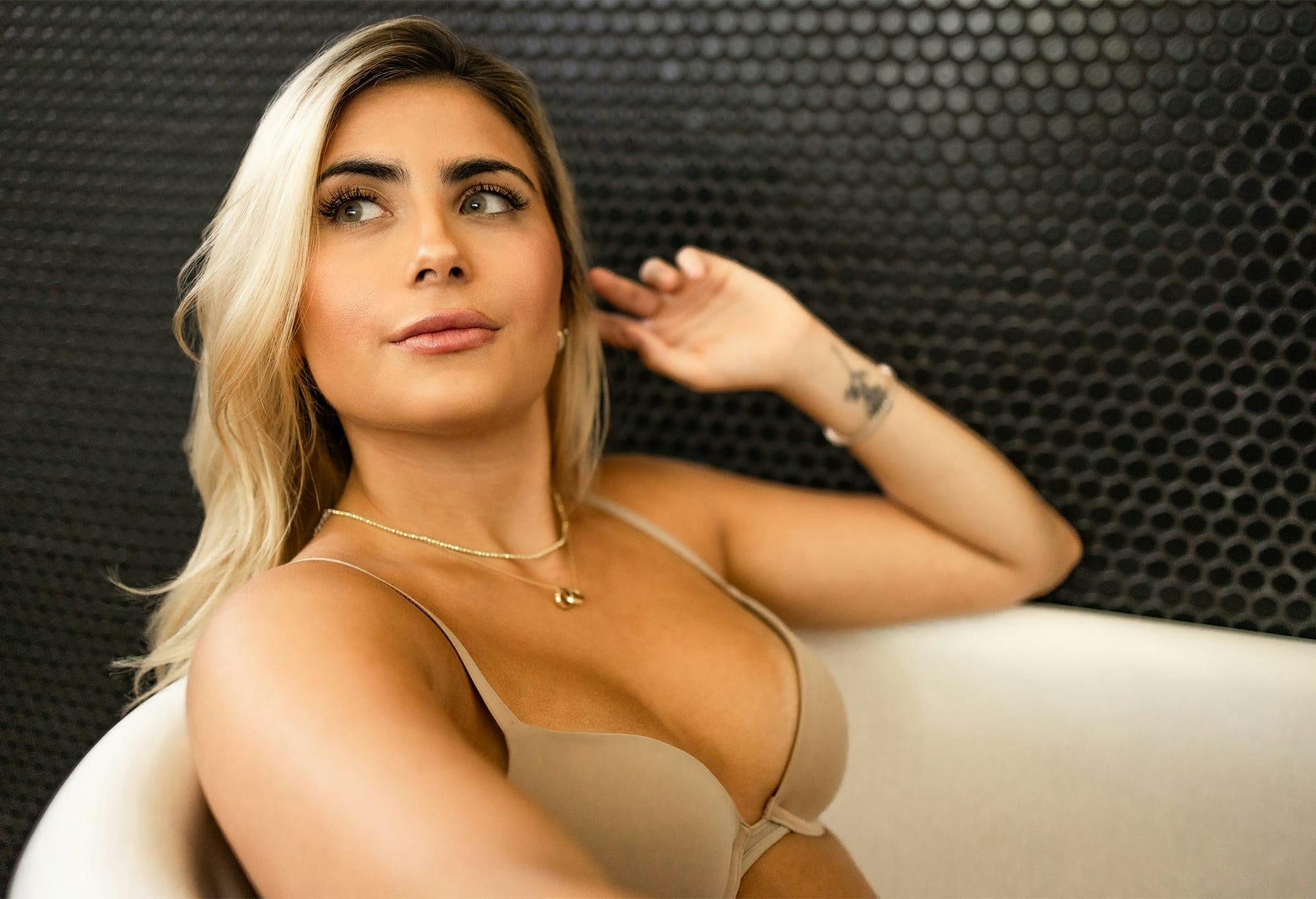 Woman wearing bra sitting in bathtub