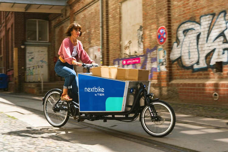 A women delivering parcels in the last mile with a cargobike A women delivering parcels in the last mile with a cargobike