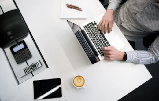 A man works on a laptop with a coffee