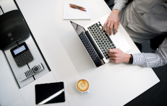 A man works on a laptop with a coffee