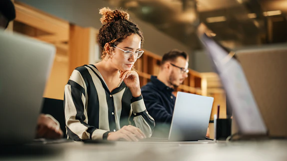 A woman looking at a laptop on a desk