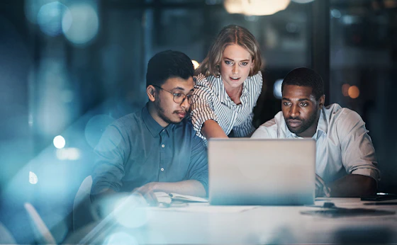 Three people looking at a laptop