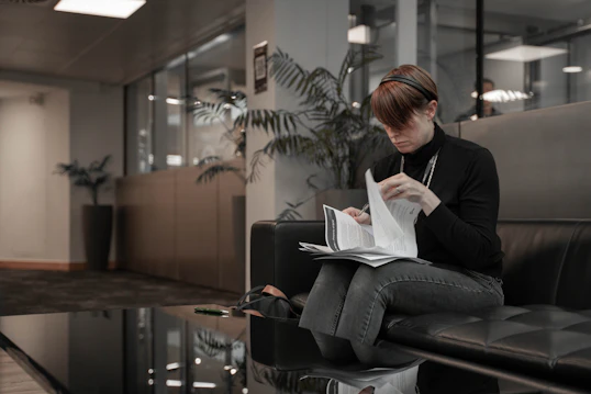A woman reading documents while sitting on a sofa