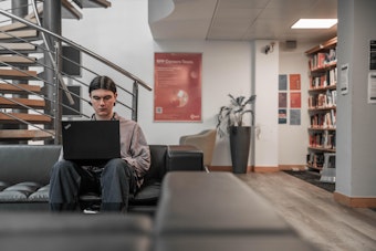 A student sits on a sofa across a sign that says BPP University Law School