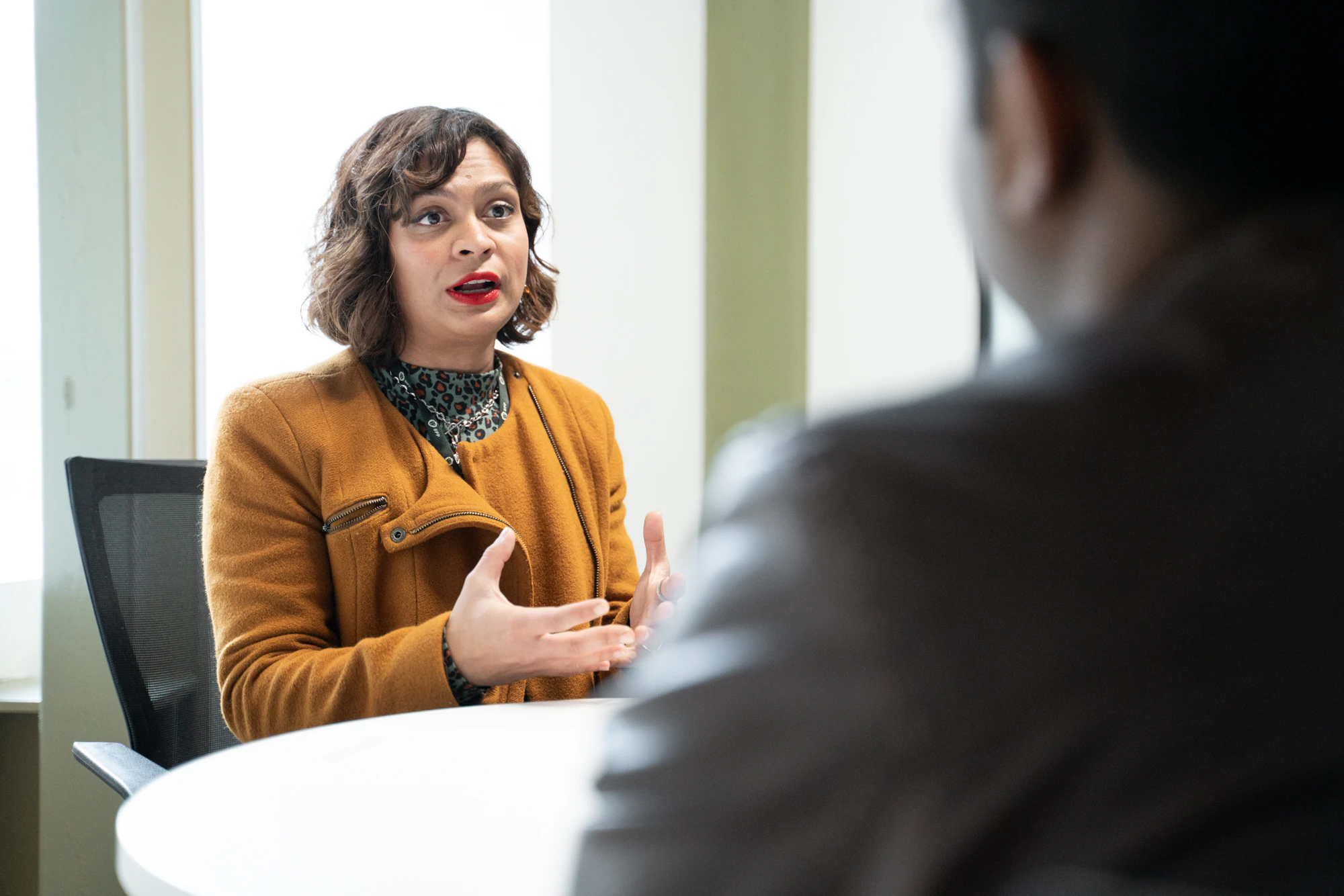 A female tutor speaks to a male student across a desk