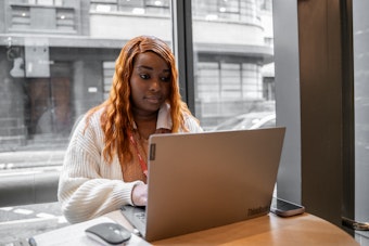 A woman sits in a cafe on a laptop computer