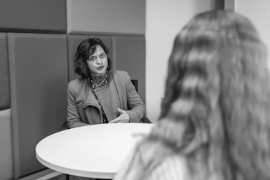 A female lecturer speaks to a female student across a white table