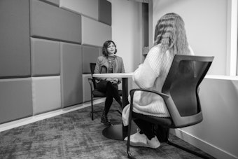 A female lecturer speaks to a female student across a desk
