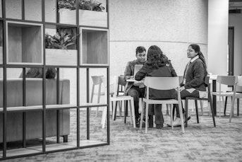 Three students sit at a desk