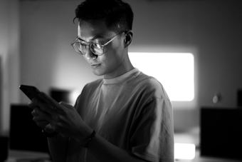 A black and white image of a young man looking at a mobile phone