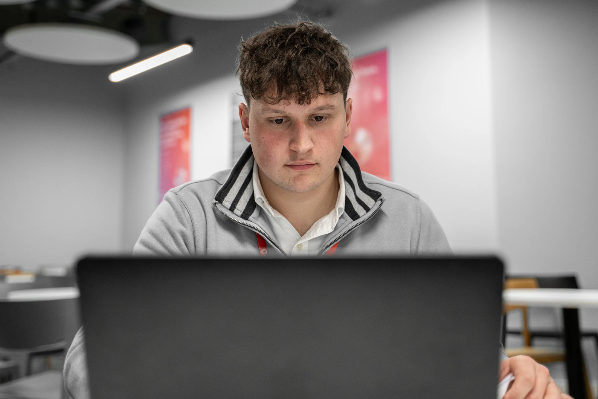 A young male sits infront of a laptop computer