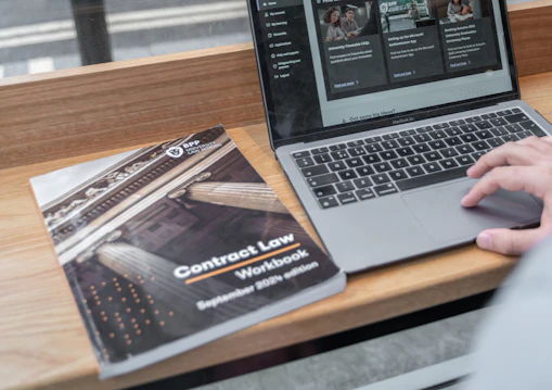 A Contract Law book sits next to a laptop computer on a desk