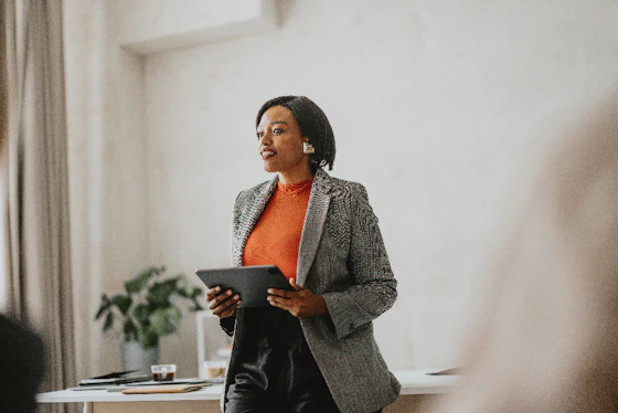 A woman stands as she presents while holding a tablet computer