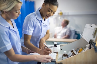 Two female nurses look over medicine