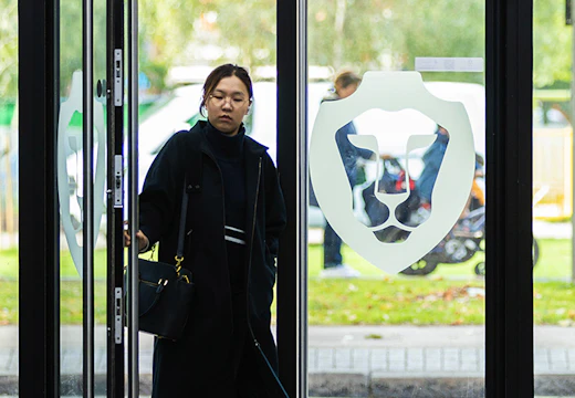 A woman walks through two glass doors with the BPP lion emblem on them