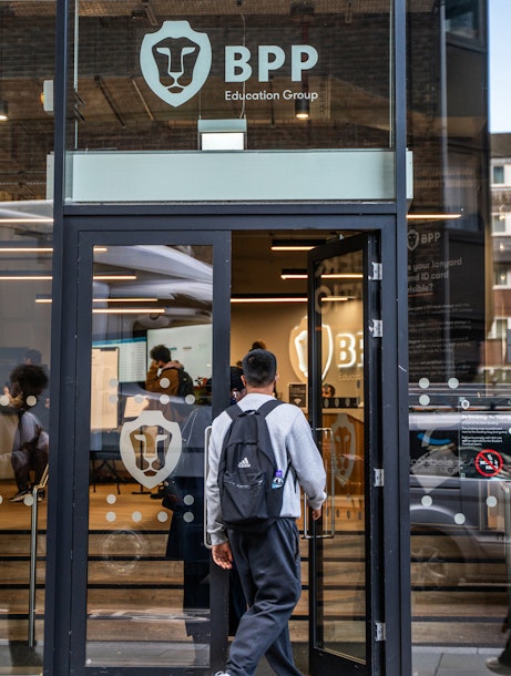 A male student walks through the glass doors of a BPP centre