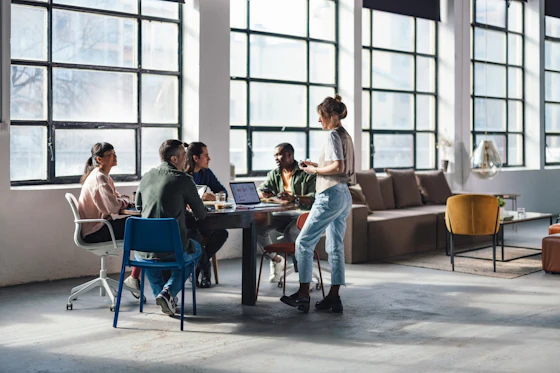 A group of men and women sit around a desk in a modern office space