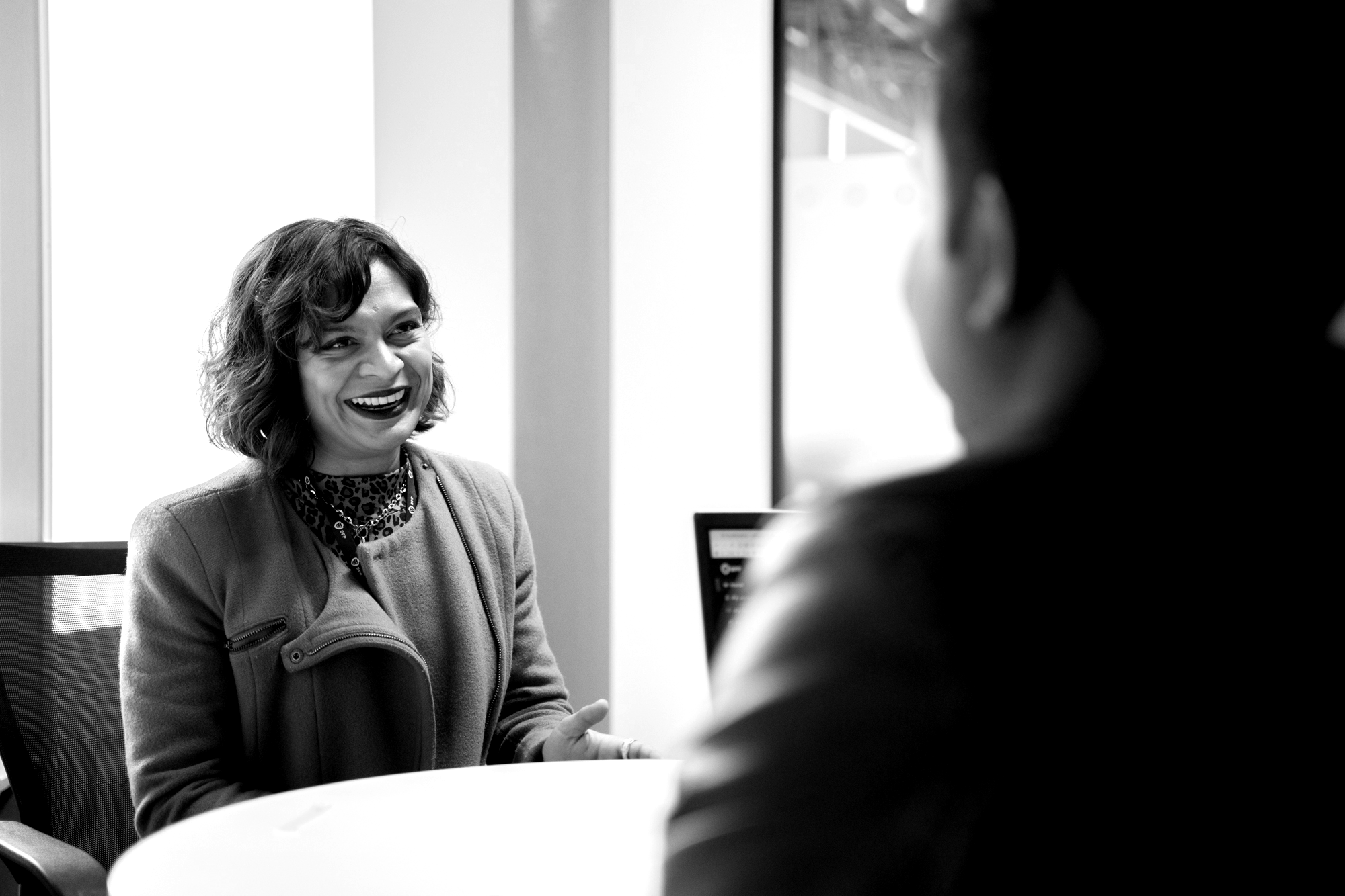 A female lecturer speaks to a male student across a desk