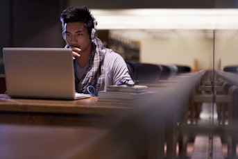 Student looking at a laptop with headphones on