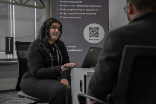 A male and female member of staff speak to a student across a desk