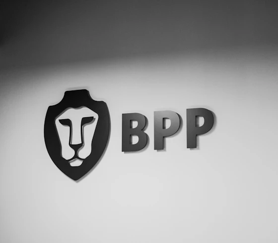 A black and white image of the BPP logo against a wall
