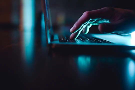 Hand typing on a laptop Hand typing on a laptop in the dark