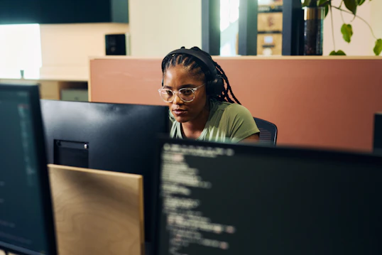 Software developer at a workstation A developer working at a desk with multiple monitors displaying code.