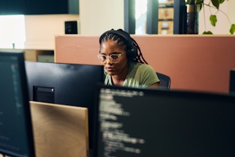 A developer working at a desk with multiple monitors displaying code.