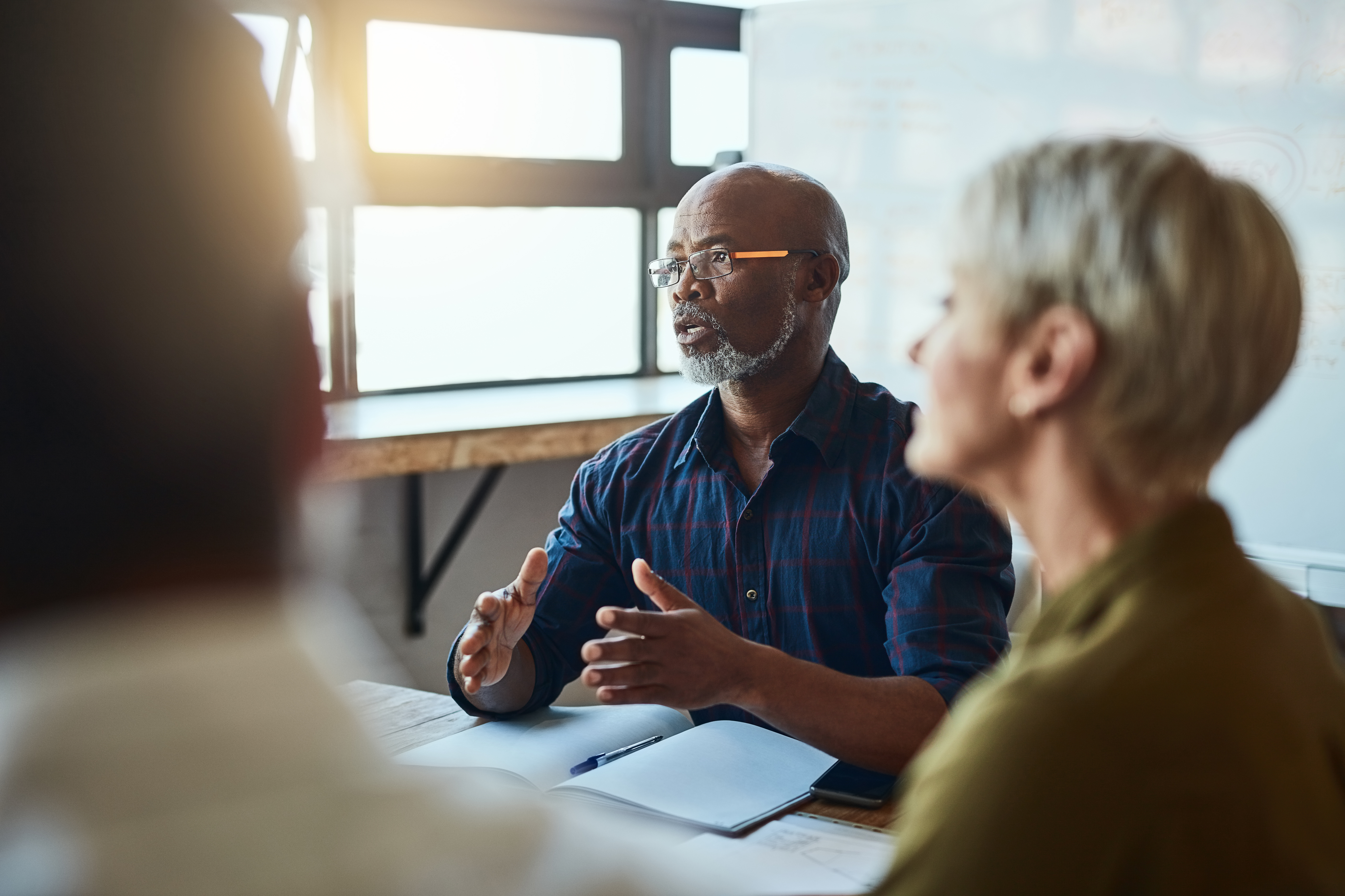People having a meeting at a boardroom table with someone gesturing.