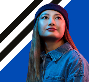 A woman in a blue denim shirt and blue beanie hat looks into the distance
