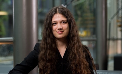 Portrait of a person with long wavy hair in an office setting.