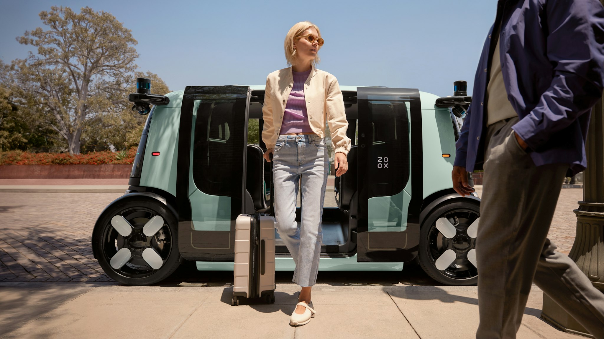 A woman exiting a Zoox robotaxi with her luggage