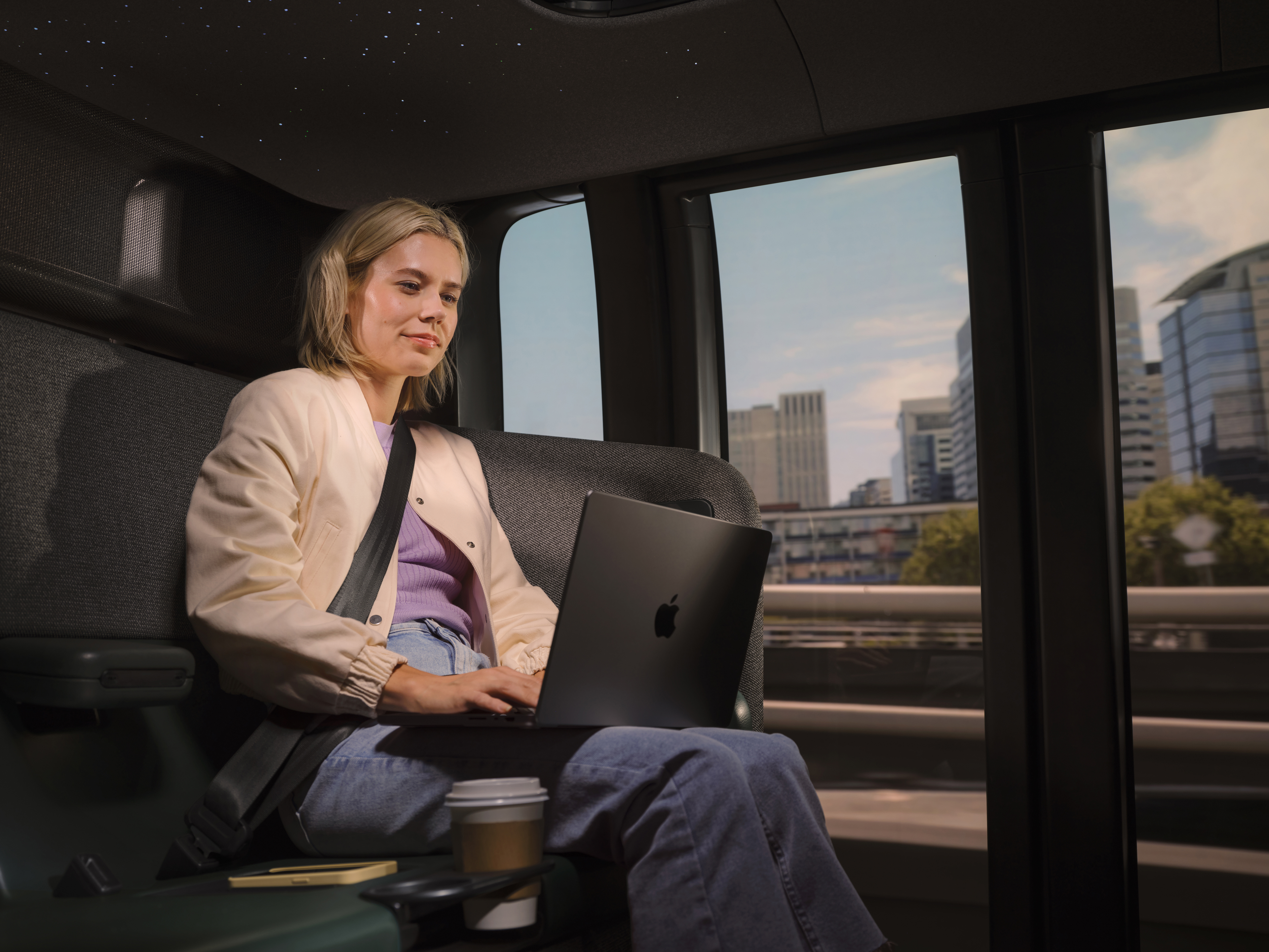 A woman working on a laptop in a Zoox vehicle