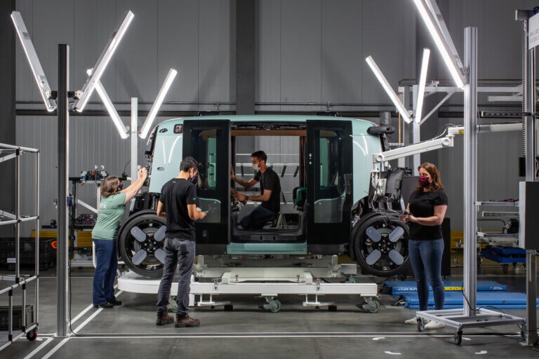 Zoox employees inspect a Zoox vehicle