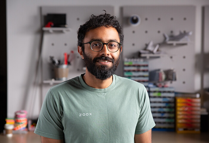 Zoox employee Abishek in front of a wall of tooling