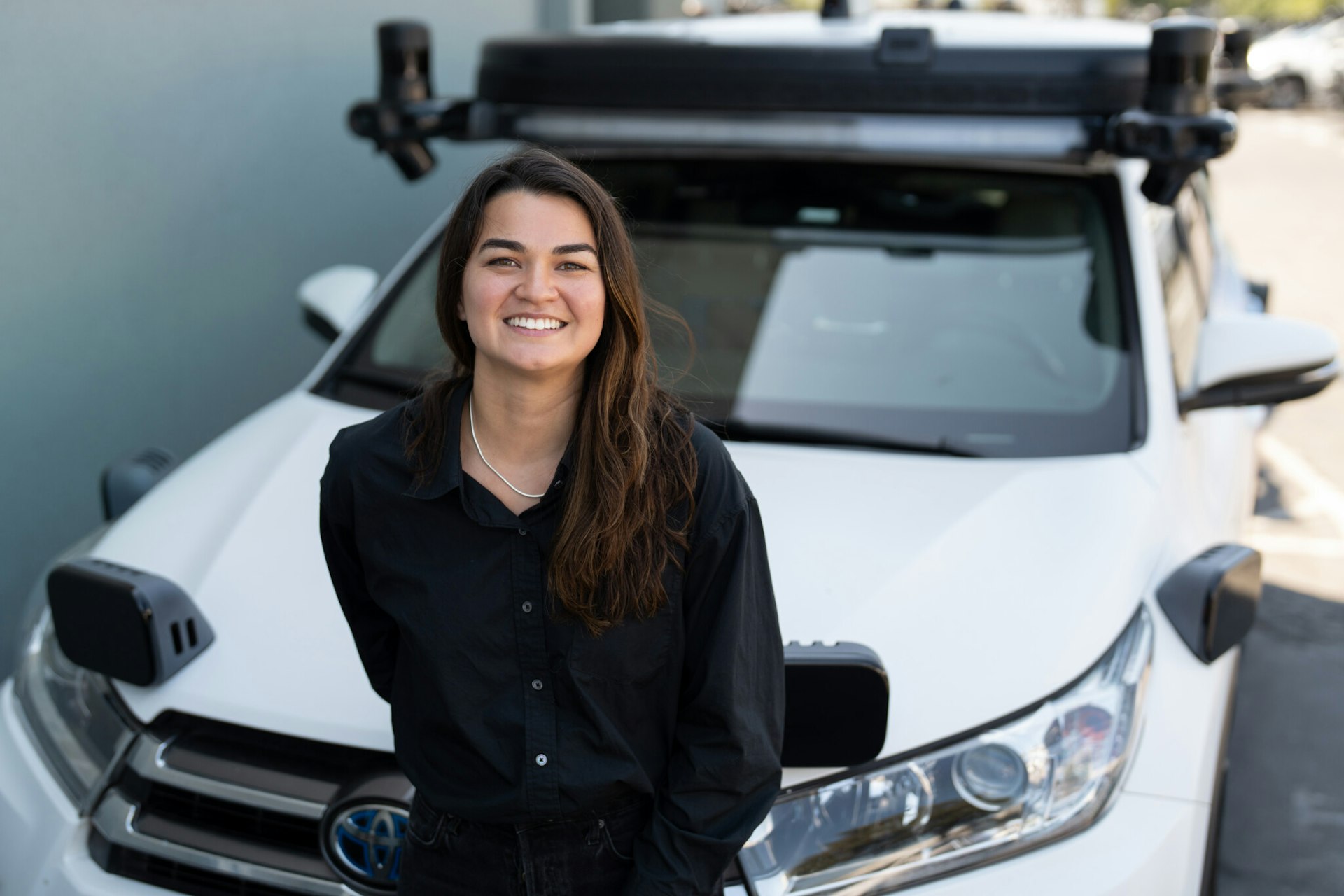 Zoox employee stephanie in front of a zoox test vehicle toyota highlander