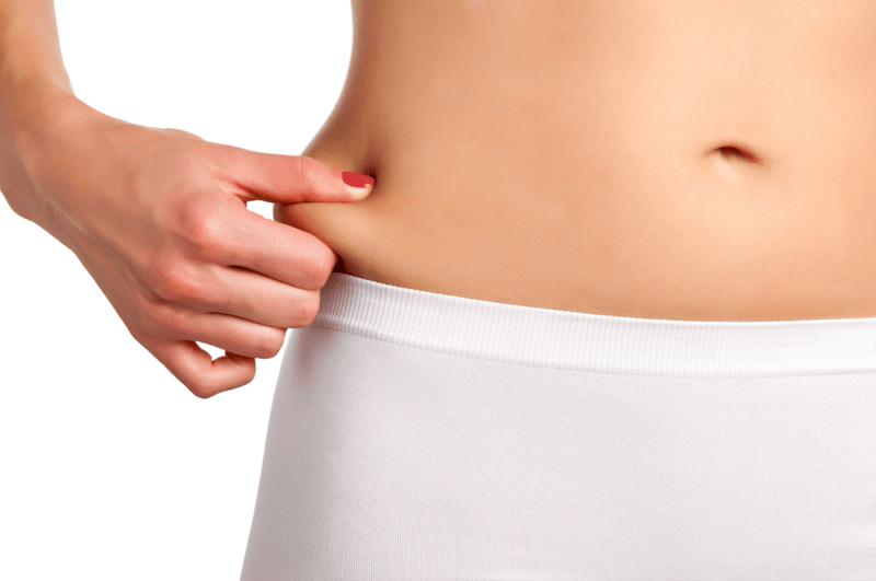 close up of a woman's waist and her hand pinching her fat