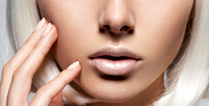 close up of a blond woman's face and her hand on her cheek