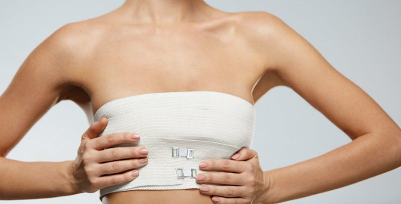 woman in a white chest bandage wrap with her hands on her chest