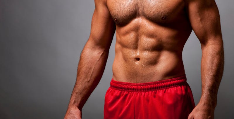 close up of a man's abs in now shirt and red shorts posing for a picture